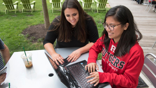 Rutgers students outside working on a laptop