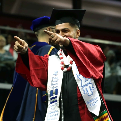 SC&I Student points excitedly into the crowd on Graduation Day