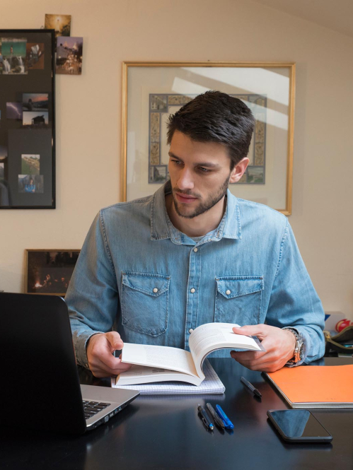 Student at desk with book and computer