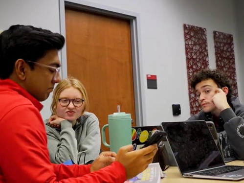 Students in discussion around laptop