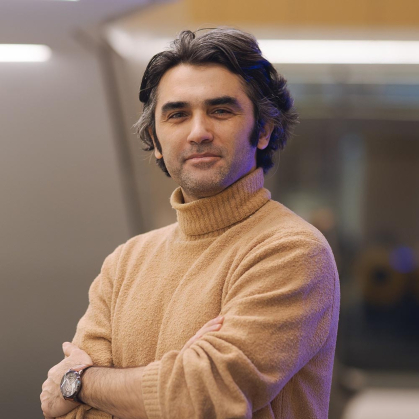 Ali Motamedi, in this headshot, is wearing a camel colored turtleneck sweater.